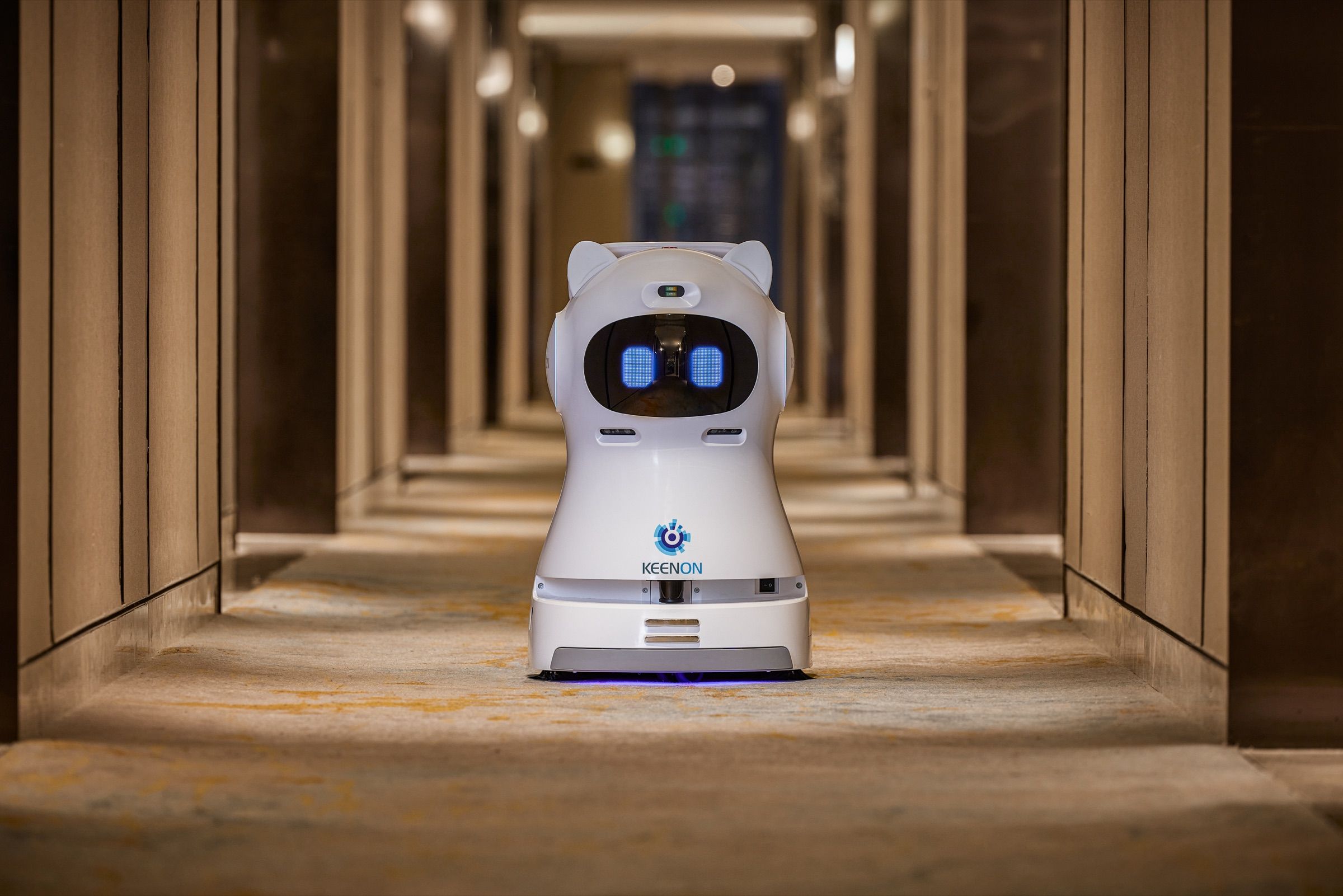 Cleaning robot vacuuming a carpeted hotel corridor