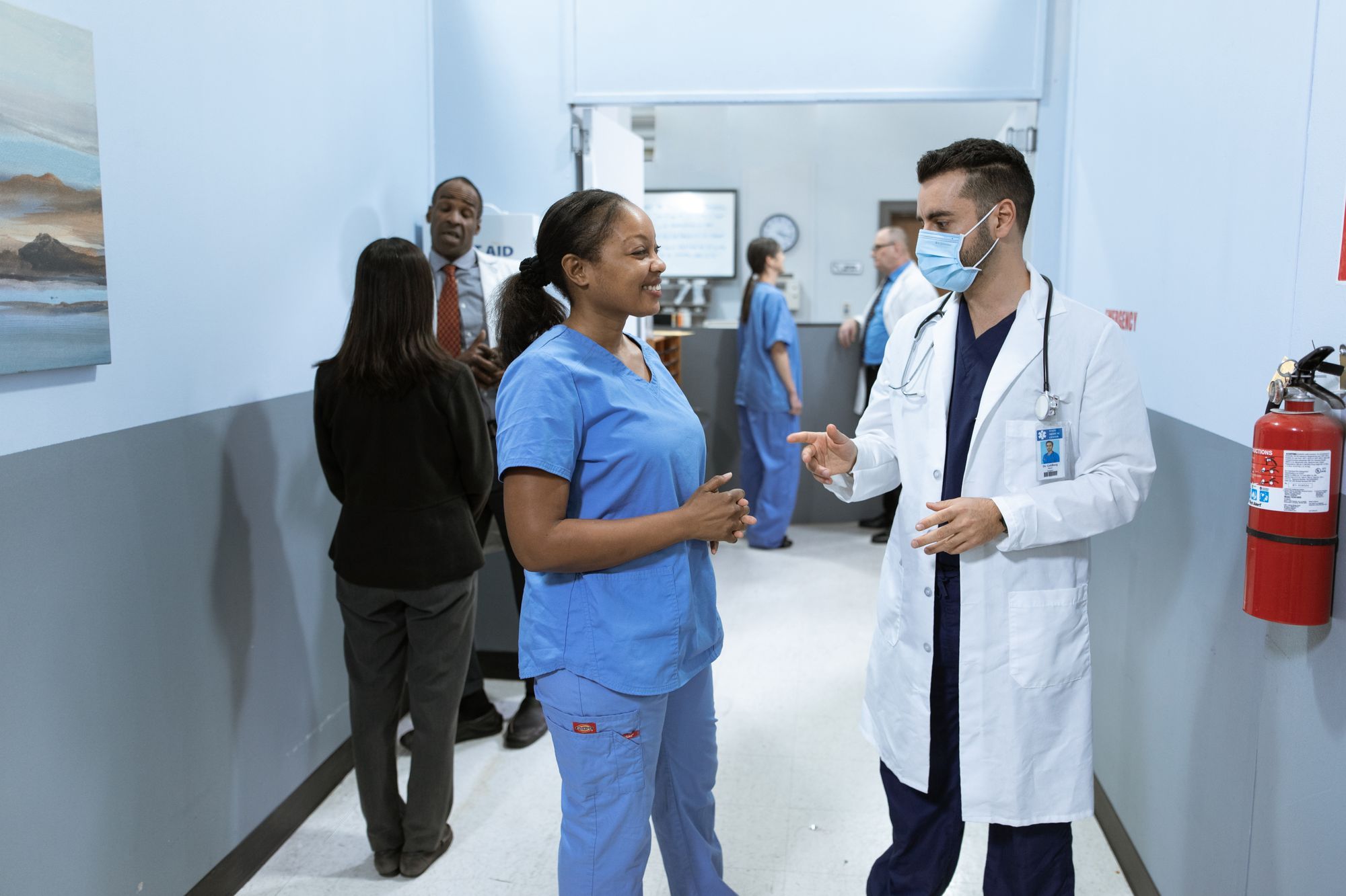 Nurses and a doctor talking in a bright hospital corridor